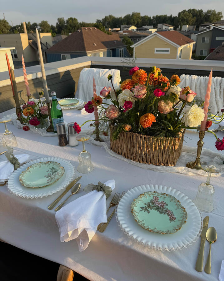 Fenton Silvercrest milk glass layered with hand-painted Limoges and yellow Depression glass creates a luminous rooftop table made for summer gathering.