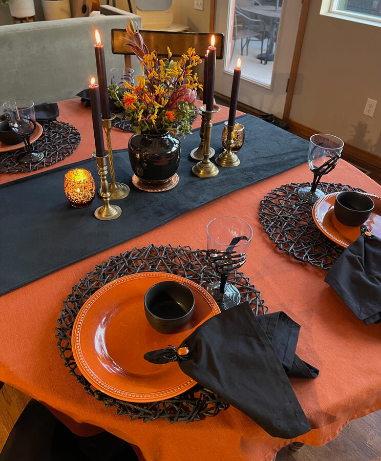 Copper tones, spider-web placemats, and playful skeleton goblets create a Halloween table that is just a little delightfully spooky.